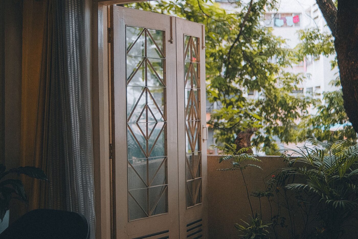 Prosklené dvoukřídlé dveře otevřené na balkon s květinami